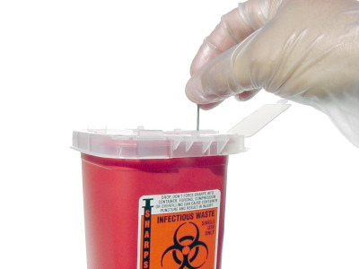 Red sharps container with biohazard symbol for safe disposal of needles and medical sharps.